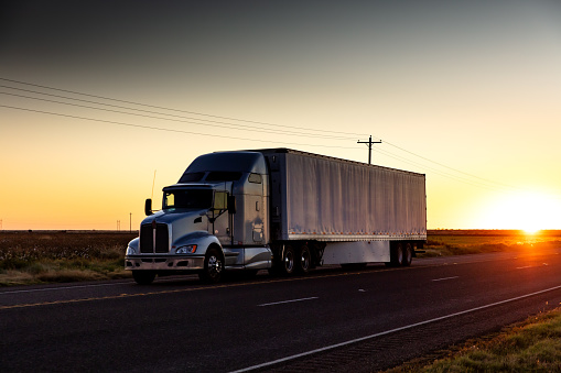 Semi-truck on a lonely highway in Texas at sunset.