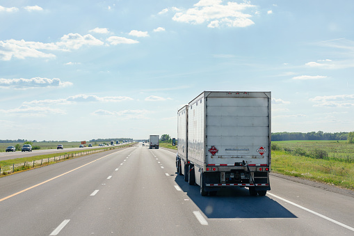 Delivery trucks driving on the highway on a sunny day. FedEx truck and cars in traffic. Federal Express is leader company in the delivery business.